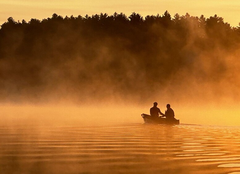 A boat with two people on a calm lake at sunrise or sunset. 4