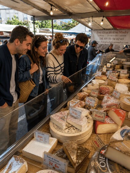 A cheese market stall with various types of cheese displayed in a glass case. 3