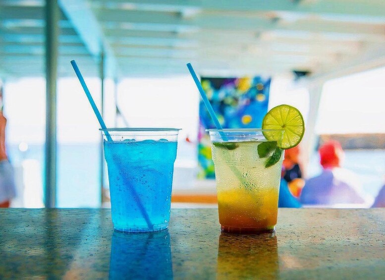 Two drinks on a bar counter with a blurred background of people and a colorful painting. 5