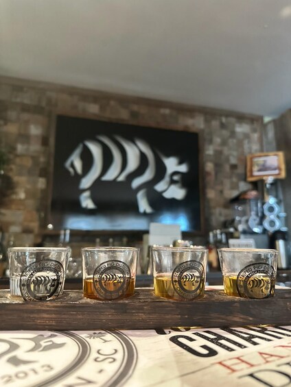 Cuatro vasos de chupito con un logo de cerdo sobre una barra de madera. 1