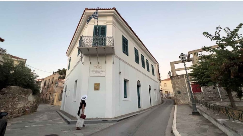 A white building with a balcony, a street, and a person walking. 5