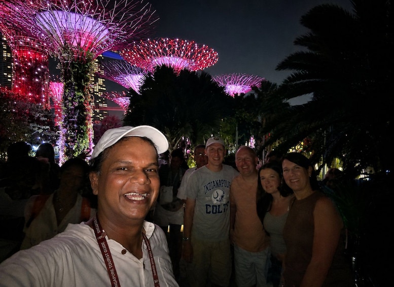 A group of people at a nighttime event with illuminated structures and trees. 1