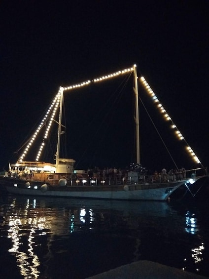 A boat with people on board, docked at a pier with lights. 3