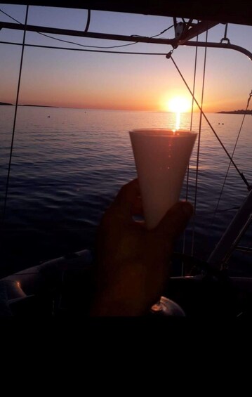 A sunset over the ocean with a hand holding a cup. 5