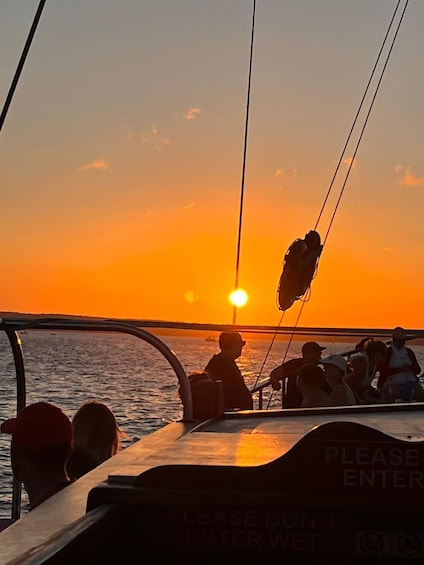 A sunset over the ocean with a boat and people on board. 4