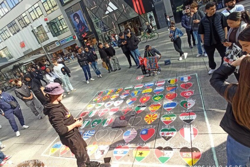 A public square with a chalk drawing of various national flags and hearts. 3