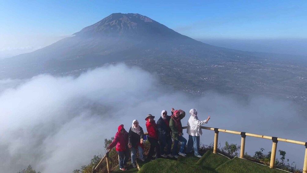 A group of people standing on a viewing platform with a mountain in the background. 3