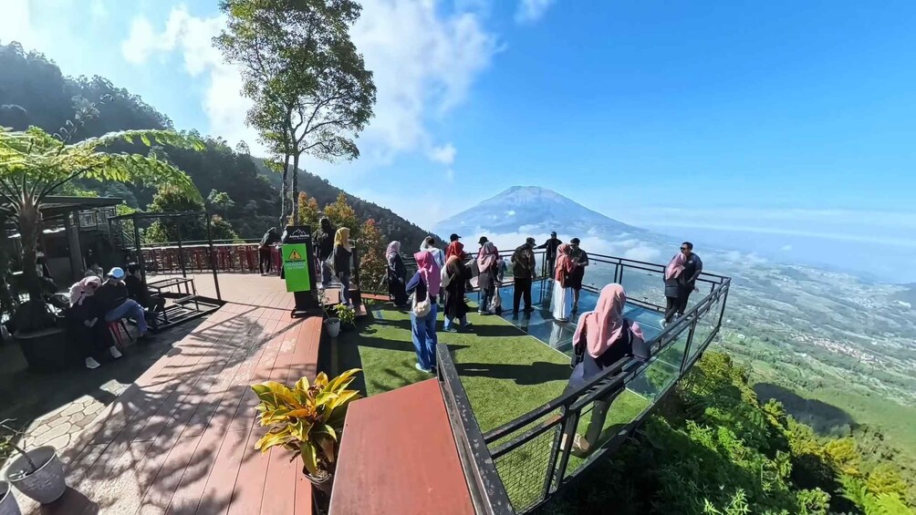 A group of people on a glass bridge overlooking a mountain and a valley. 4