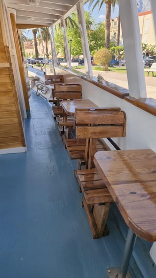 A covered outdoor seating area with wooden tables and benches. 5