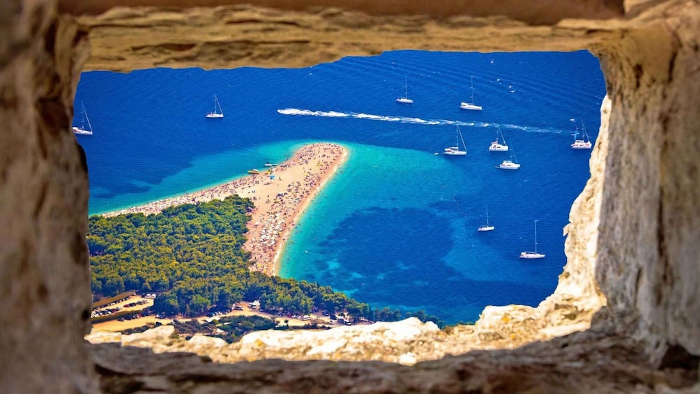 A coastal landscape with a beach, boats, and a rocky cliff. 1
