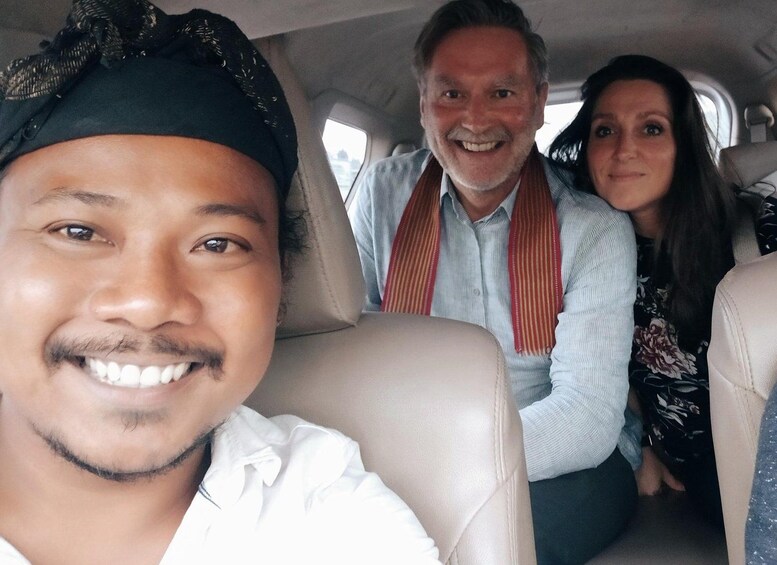 Tres personas sentadas en el interior de un coche con asientos de cuero color beige. 3