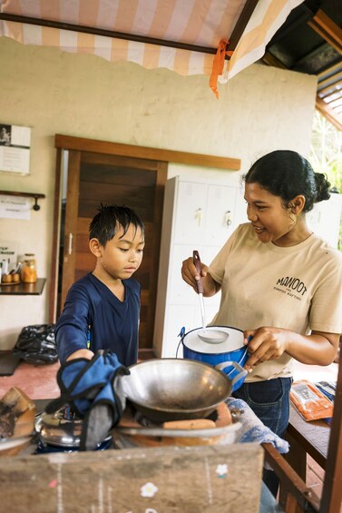 A person cooking with a pot on a stove, another person holding a ladle, and a kitchen setting with a checkered ceiling. 5