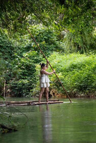 A person standing on a floating platform in a river, surrounded by dense greenery. 2