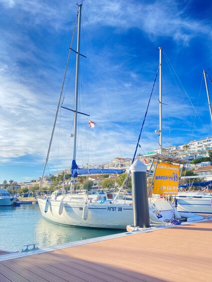 A marina with sailboats docked, a clear blue sky, and a sign advertising a boat rental service. 4