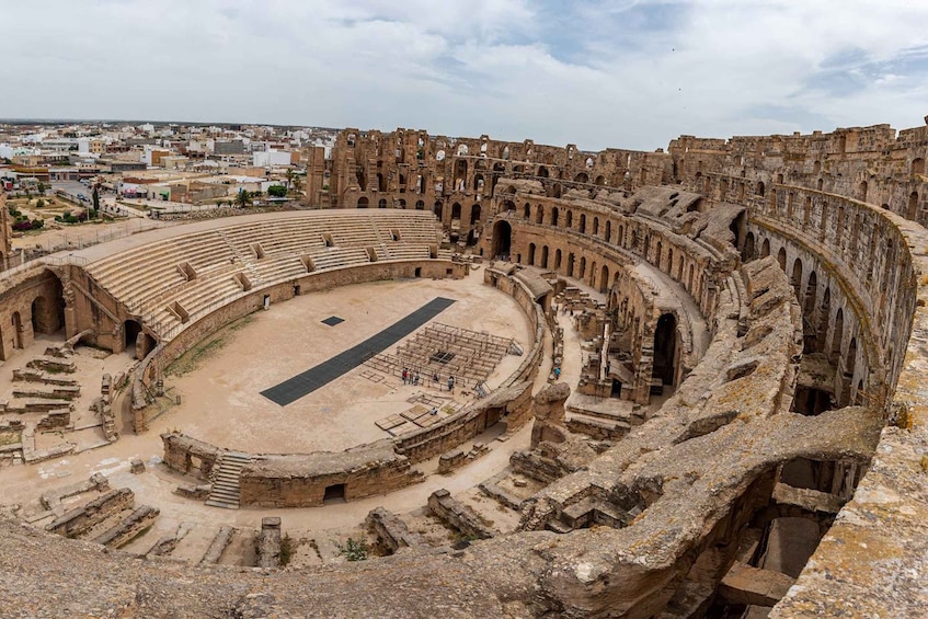An ancient amphitheater with a central stage and tiered seating. 2
