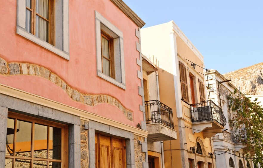 A pink building with a stone base, a white building with a balcony, and a mountain in the background. 2
