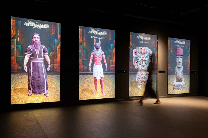 A museum exhibit with three large digital displays. 3
