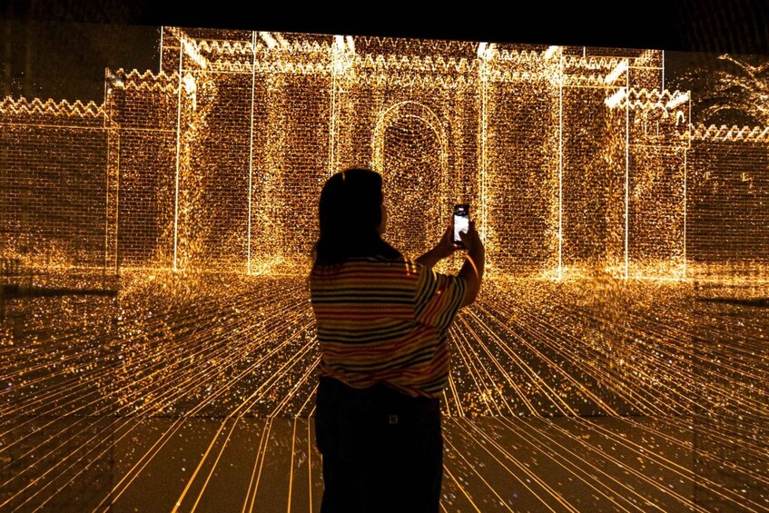 A person taking a photo of a light installation with a grid pattern. 4