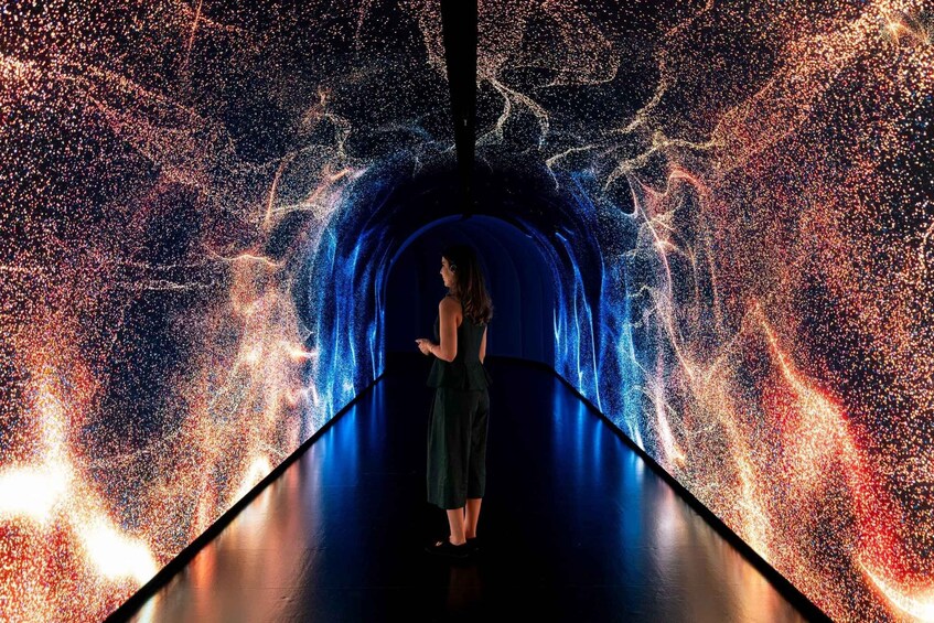 A person standing in a tunnel with a digital display of a starry sky. 2