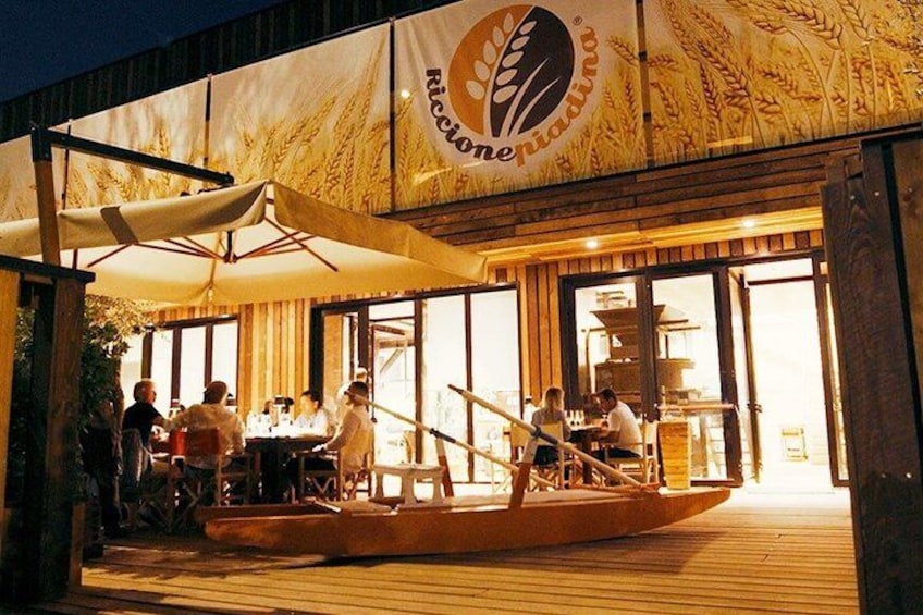 An outdoor dining area with a boat, tables, and people. 4