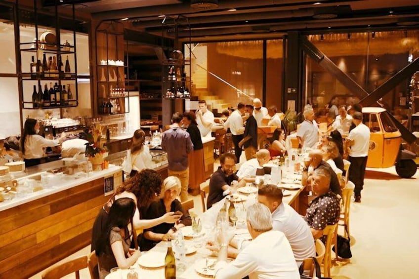 A busy restaurant with patrons dining and staff attending to them. 2