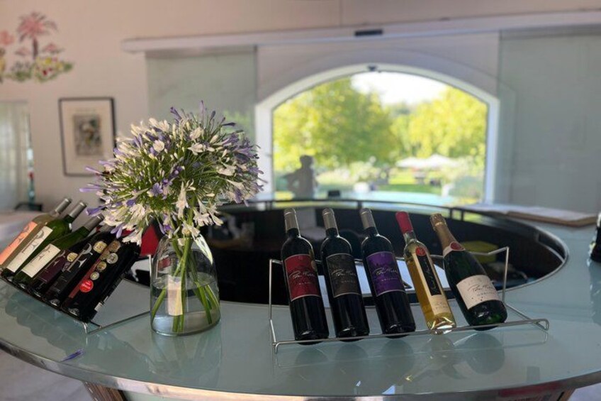 A glass table with wine bottles and a vase of flowers. 3