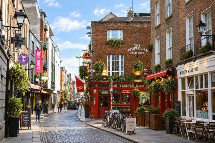 A cobblestone street lined with brick buildings, a red pub named 'The Temple Bar,' and a cafe called 'Brick Alley Cafe.' 2