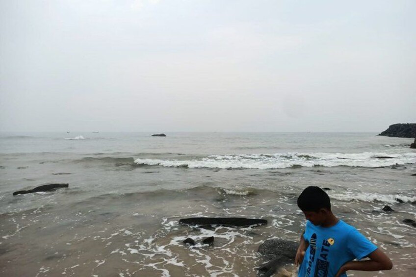 A beach with waves, rocks, and a person in a blue shirt. 2