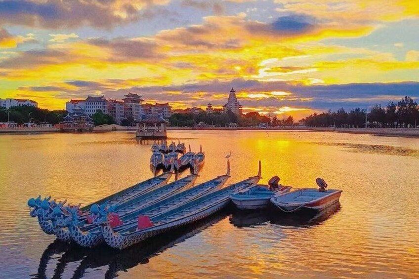 A dragon boat at sunset with traditional Chinese architecture in the background. 1