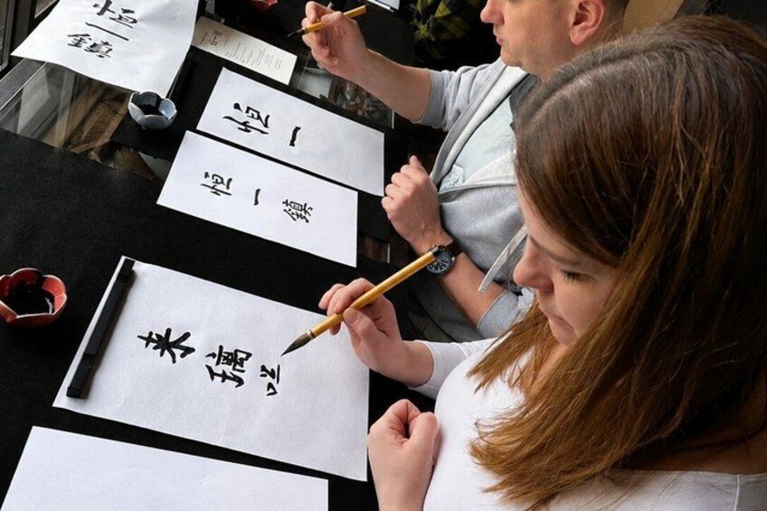 People practicing calligraphy with brushes on paper. 1