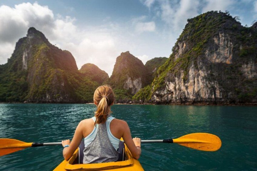 A person kayaking on a calm sea with mountainous landscape in the background. 1