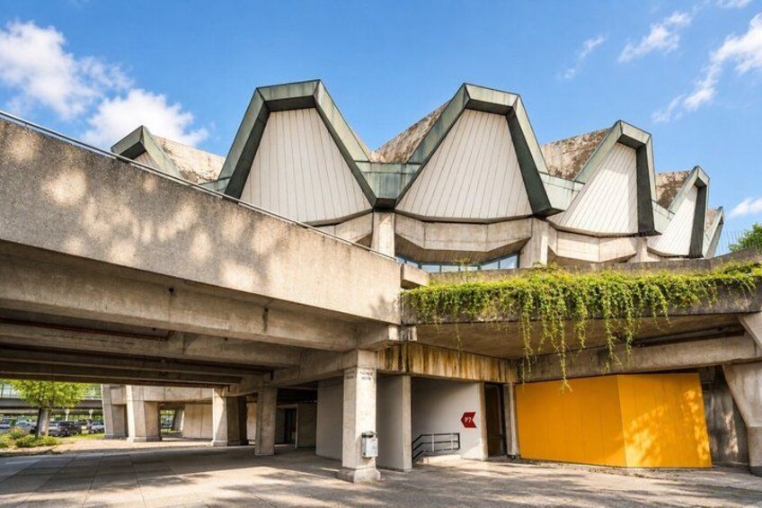 A modern building with a unique architectural design, featuring multiple angular roofs and a covered entrance. 5