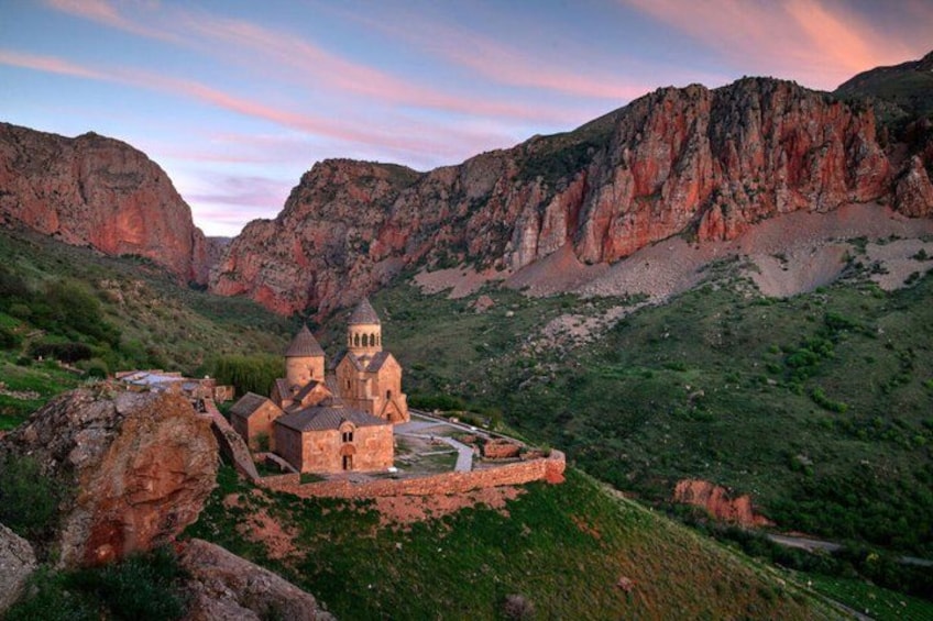Una iglesia con dos torres, rodeada de colinas rocosas y vegetación. 2