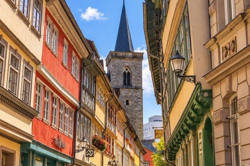 A street with colorful buildings, a church tower, and hanging flower baskets. 3