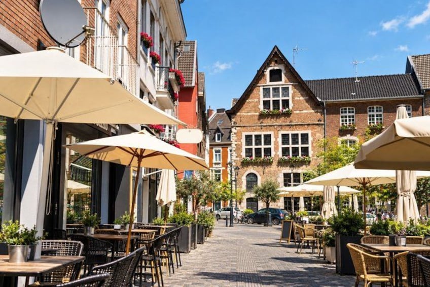 Une rue pavée bordée de cafés en plein air, de bâtiments en briques et de jardinières fleuries. 4