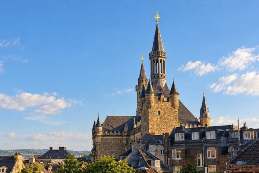 Un bâtiment historique en pierre, doté de nombreuses flèches et d’un imposant clocher abritant une horloge. 2