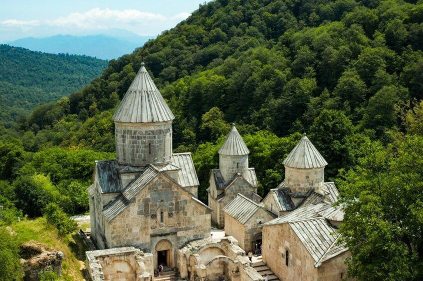 A historic church with multiple bell towers, surrounded by lush green forest and hills. 5