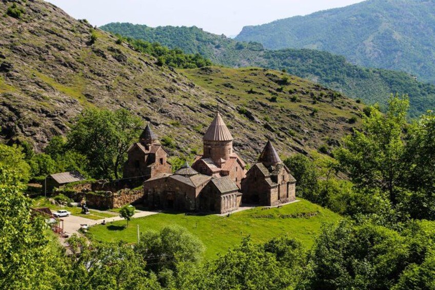 A historic church with multiple spires, surrounded by lush green hills and trees. 4