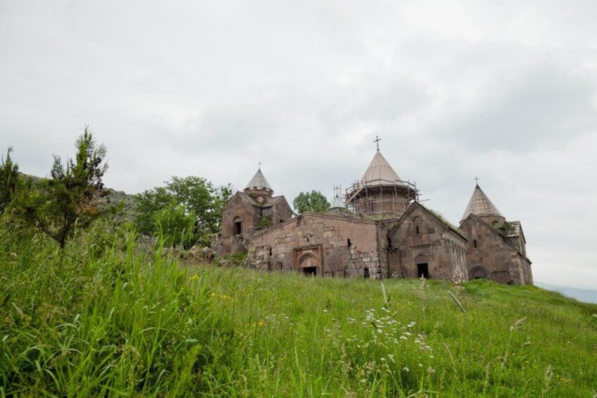 A dilapidated church with multiple domes, surrounded by overgrown grass and trees. 3