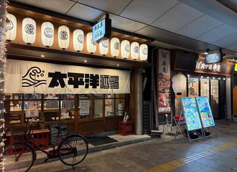 A Japanese restaurant with a large sign, traditional lanterns, and a bicycle parked outside. 4