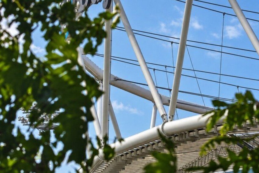 A modern architectural structure with a network of cables and beams against a clear sky. 5