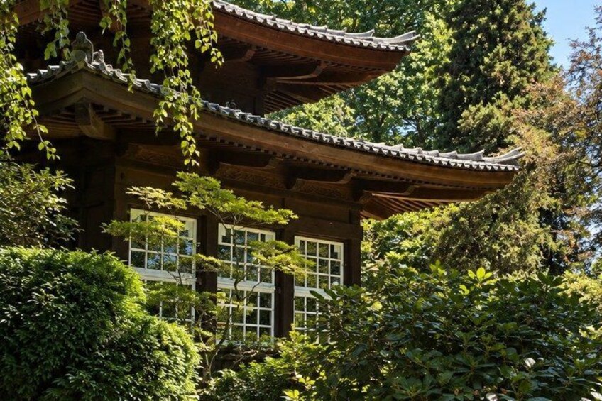 A traditional Japanese building with a tiled roof, surrounded by lush greenery and trees. 4