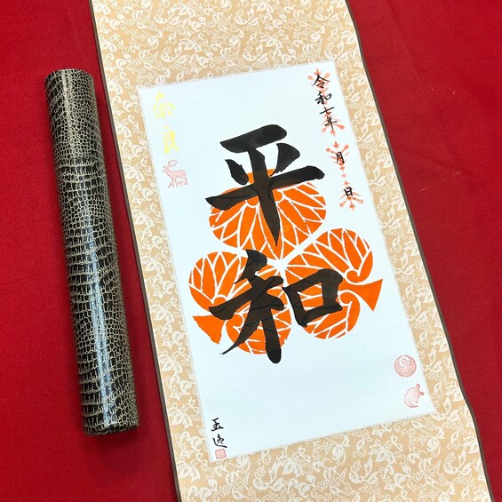 Un livre contenant des caractères japonais et une couverture décorative, posé sur une surface rouge. 1