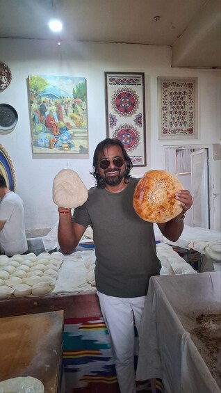 A person holding two types of flatbreads in a room with decorative wall hangings. 2