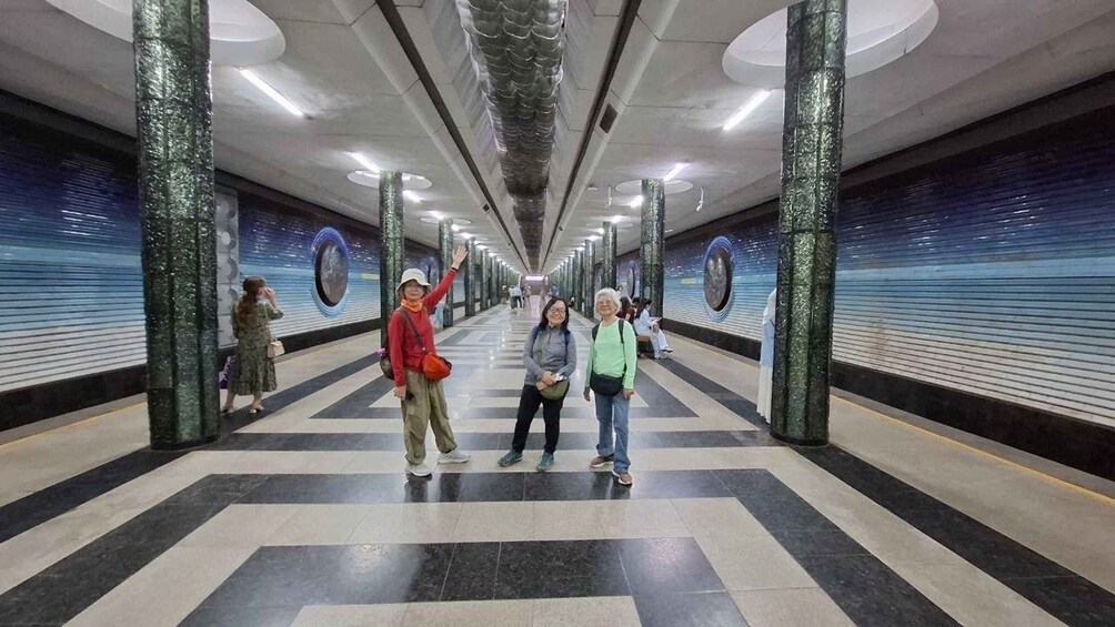 A subway station with tiled floors, green pillars, and circular wall decorations. 3