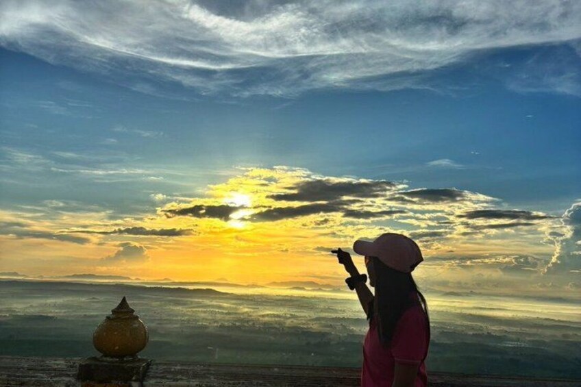 A person taking a photo of a sunset with a vase in the foreground. 3