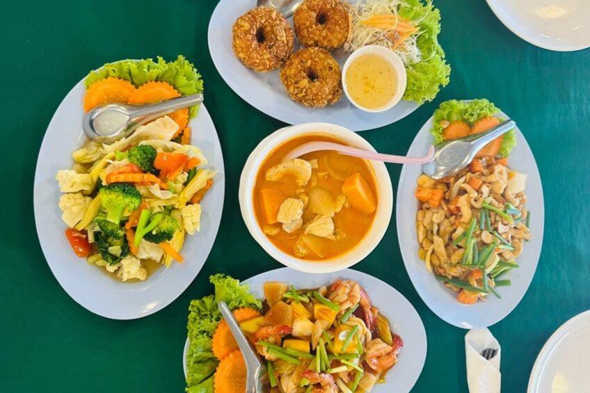 A table with various dishes including a vegetable stir-fry, a soup, and fried items. 5
