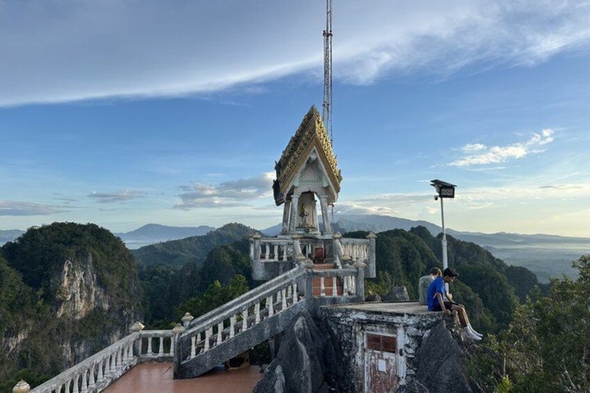 A temple on a mountain with a steep staircase, a person sitting on the edge, and a clear sky. 2