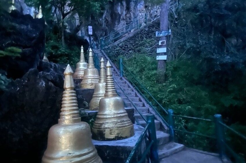 A staircase with golden spires, surrounded by greenery and a rocky cliff. 4