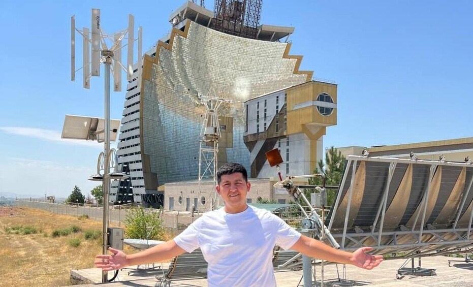 A person standing in front of a building with solar panels and antennas. 1
